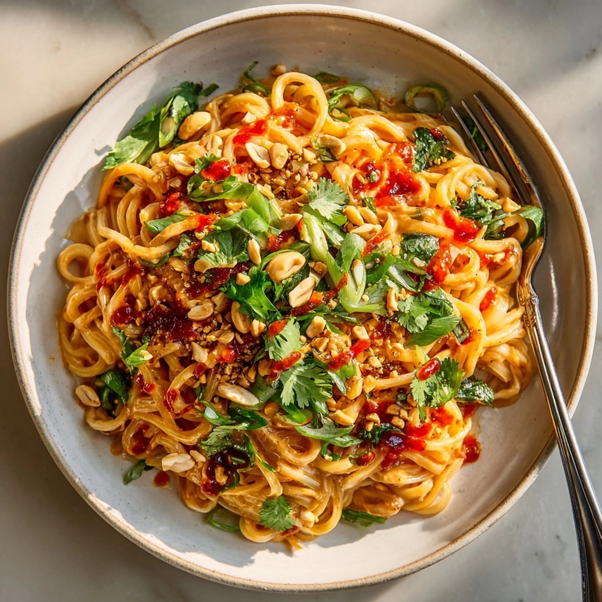 Steaming hot 10-Minute Peanut Noodles topped with chopped peanuts and fresh cilantro