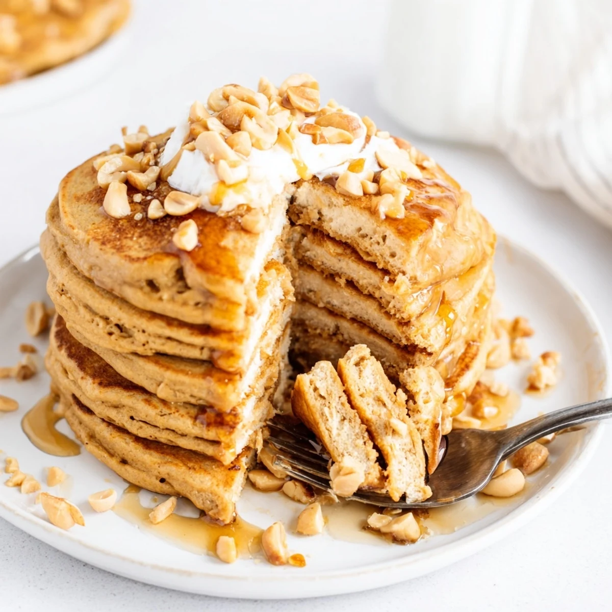 Fluffy pumpkin spice peanut butter pancakes topped with maple syrup and peanuts.  