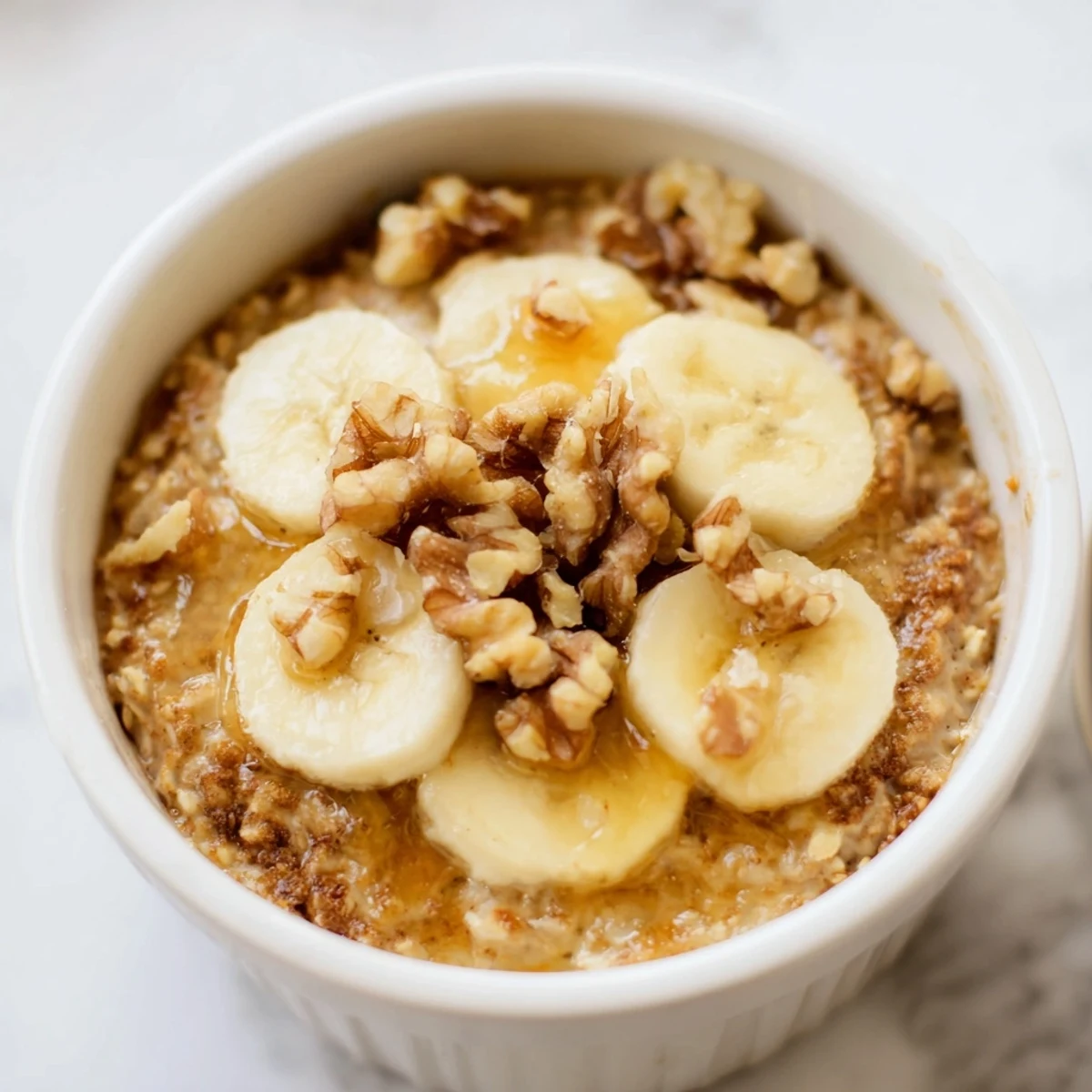 Steaming-hot, individual Baked Oats Ramekins with fresh bananas, perfect for a cozy morning breakfast.