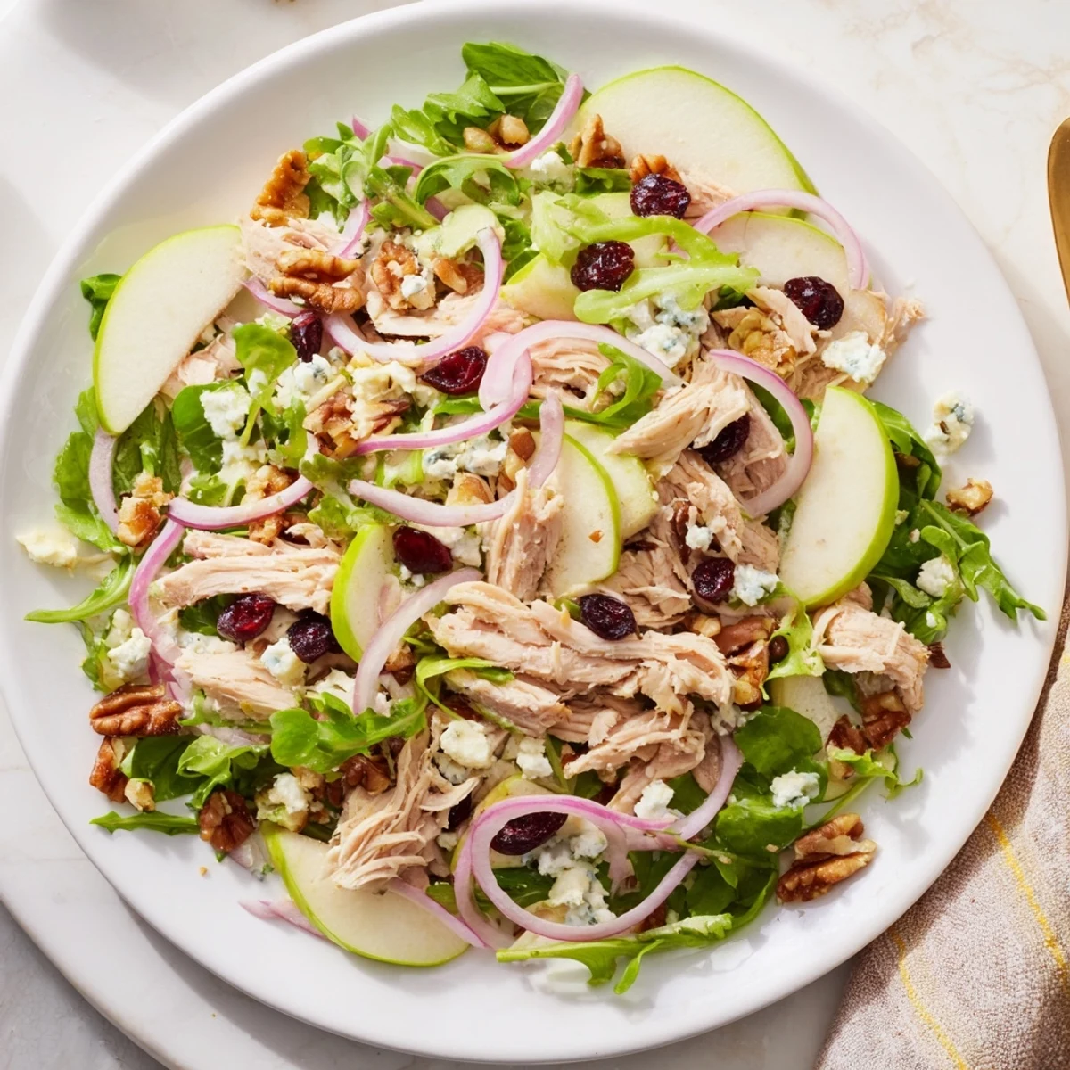 Fresh Chicken and Apple Winter Salad with colorful apples and chicken, topped with pecans.
