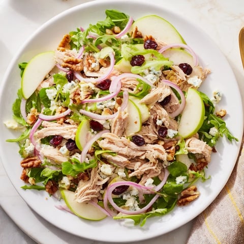 Fresh Chicken and Apple Winter Salad with colorful apples and chicken, topped with pecans.