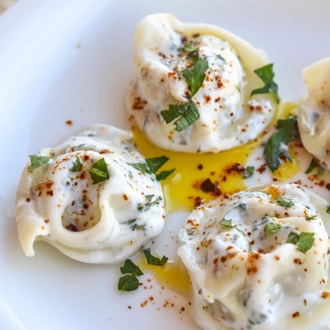 Steaming Turkish Cheesy Manti, topped with garlic yogurt and vibrant spiced butter, ready to serve.