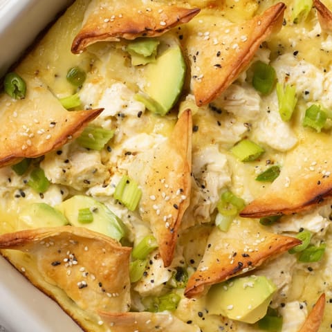 A close-up image shows the creamy Avocado Crab Rangoon Bake, scattered with sesame seeds.