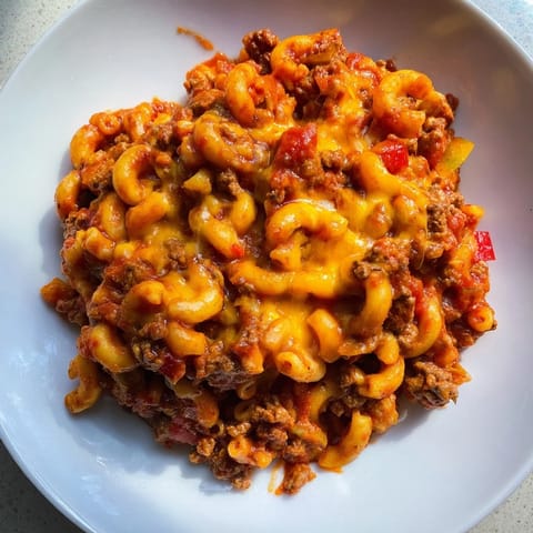 Golden, melted cheddar cheese tops a hearty oven-baked hamburger casserole, a family favorite meal.