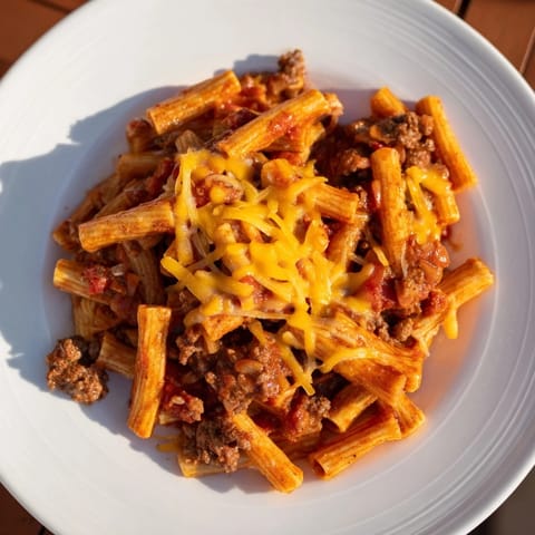 A steaming bowl of Easy Beef Enchilada Pasta, topped with melted cheddar cheese ready to eat.