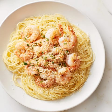 This image shows a steaming plate of One-Skillet Lemon Garlic Shrimp Angel Hair Pasta with fresh herbs.