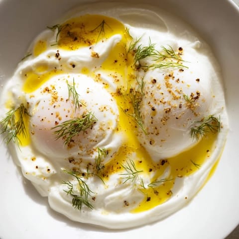 A beautiful close-up of Cilbir: rich yolk, vibrant spices, and herbed yogurt, a Turkish breakfast delight.