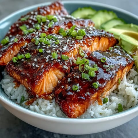 A vibrant teriyaki salmon bowl with glazed fillets, jasmine rice, and fresh avocado slices.