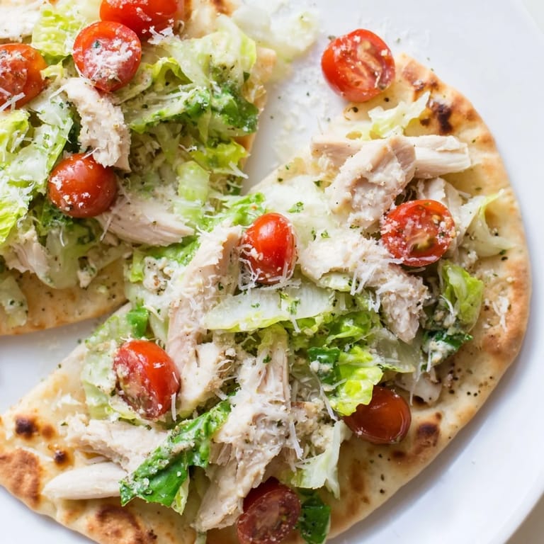 Golden-brown Chicken Caesar Flatbread with grilled chicken slices, crisp lettuce, and melted parmesan, ready for a light lunch or appetizer.