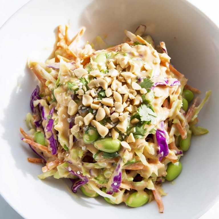 An overhead view of Crunchy Thai Peanut Salad tossed with red bell peppers and sesame seeds, ideal for a refreshing, vegan-friendly side dish.